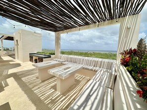 An outdoor seating area with a view of the ocean, a pergola overhead, and a small bar area. - Estudio Moderno Caribe  o  con Vista al Mar (Playa del Carmen)