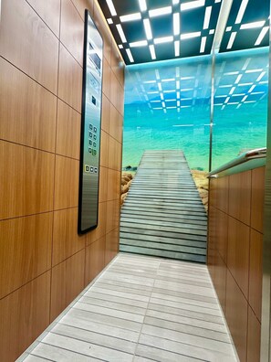 A corridor with a wooden wall, a floor-to-ceiling aquarium, and a wooden walkway leading to a dock. - Estudio Moderno Caribe  o  con Vista al Mar (Playa del Carmen)