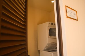 A laundry room with a washing machine and dryer, a wooden door with blinds, and a sign that reads 'Laundry Room'. - Estudio Moderno Caribe  o  con Vista al Mar (Playa del Carmen)