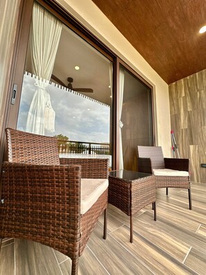 A balcony with wicker furniture, large sliding glass doors, and a view of the sky. - Boutique studio just steps from the sea (Playa del Carmen)