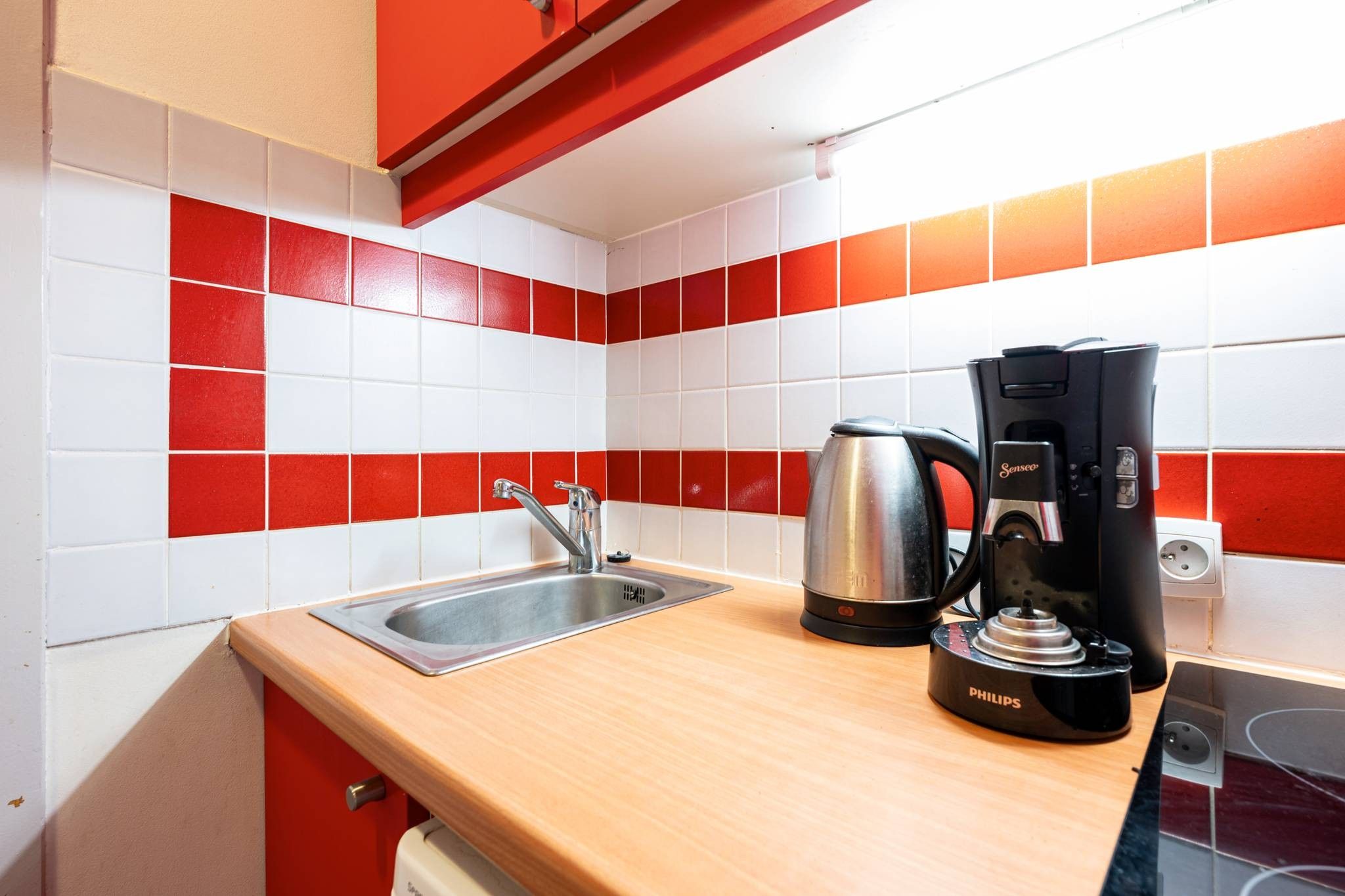 Een keuken met een spoelbak, waterkoker en koffiezetapparaat.