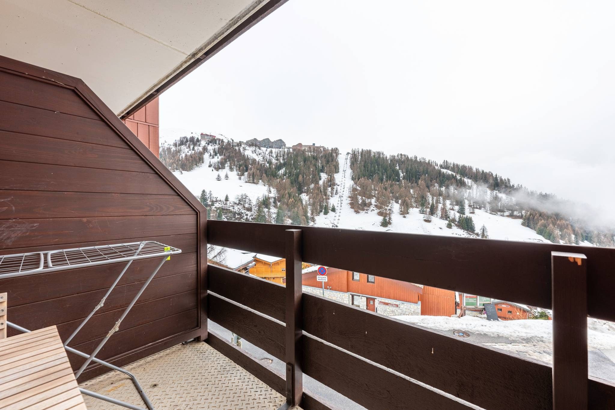 A balcony with a metal railing overlooking a snowy mountain landscape.