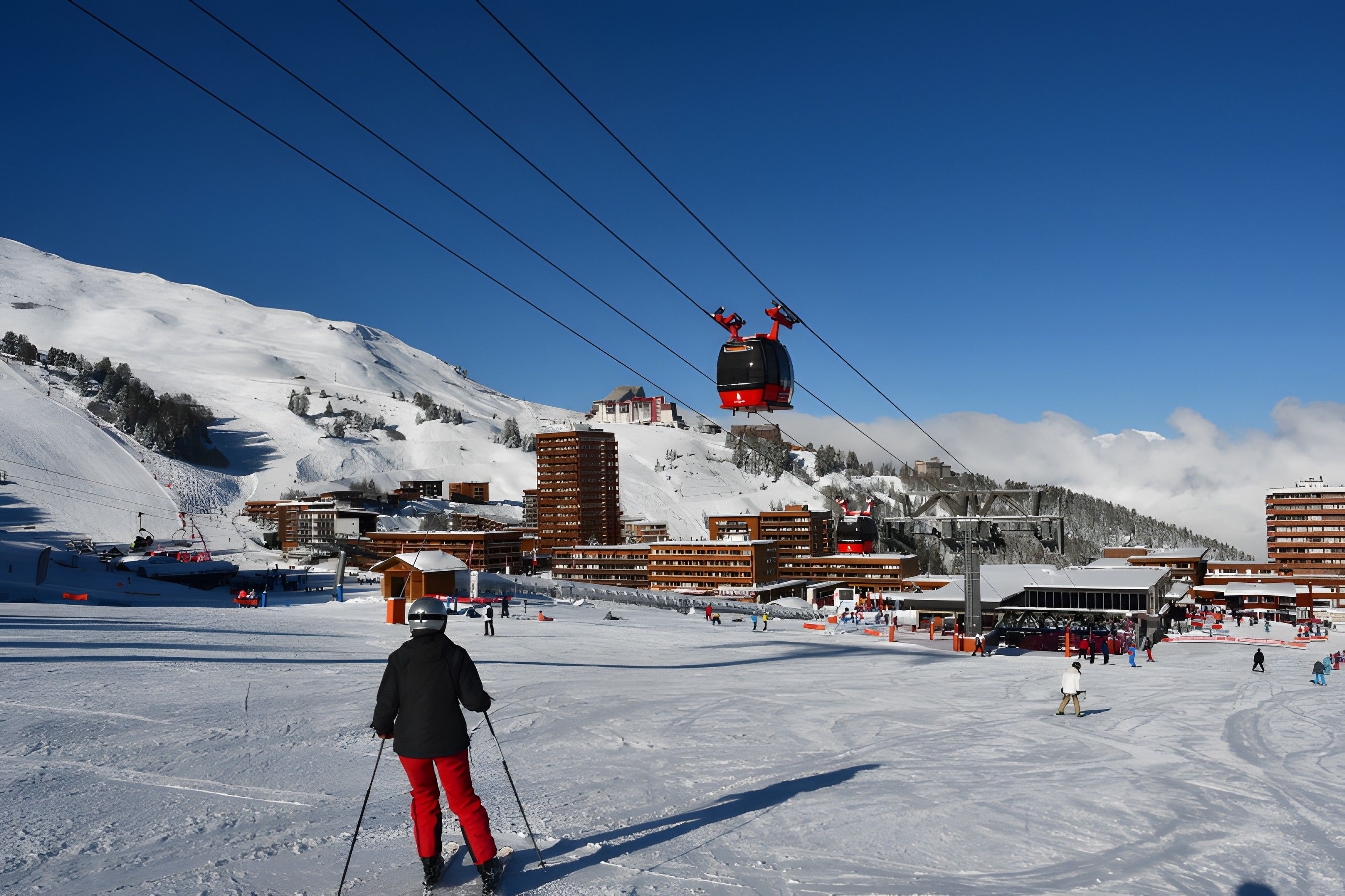 Un centro de esquí con un sistema de teleférico, pistas cubiertas de nieve y edificios de estilo arquitectónico moderno.