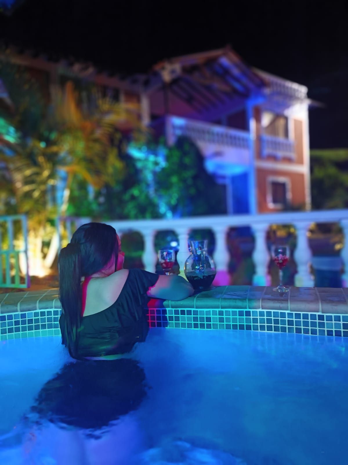 Eine Person sitzt am Pool, im Hintergrund ein Gebäude.