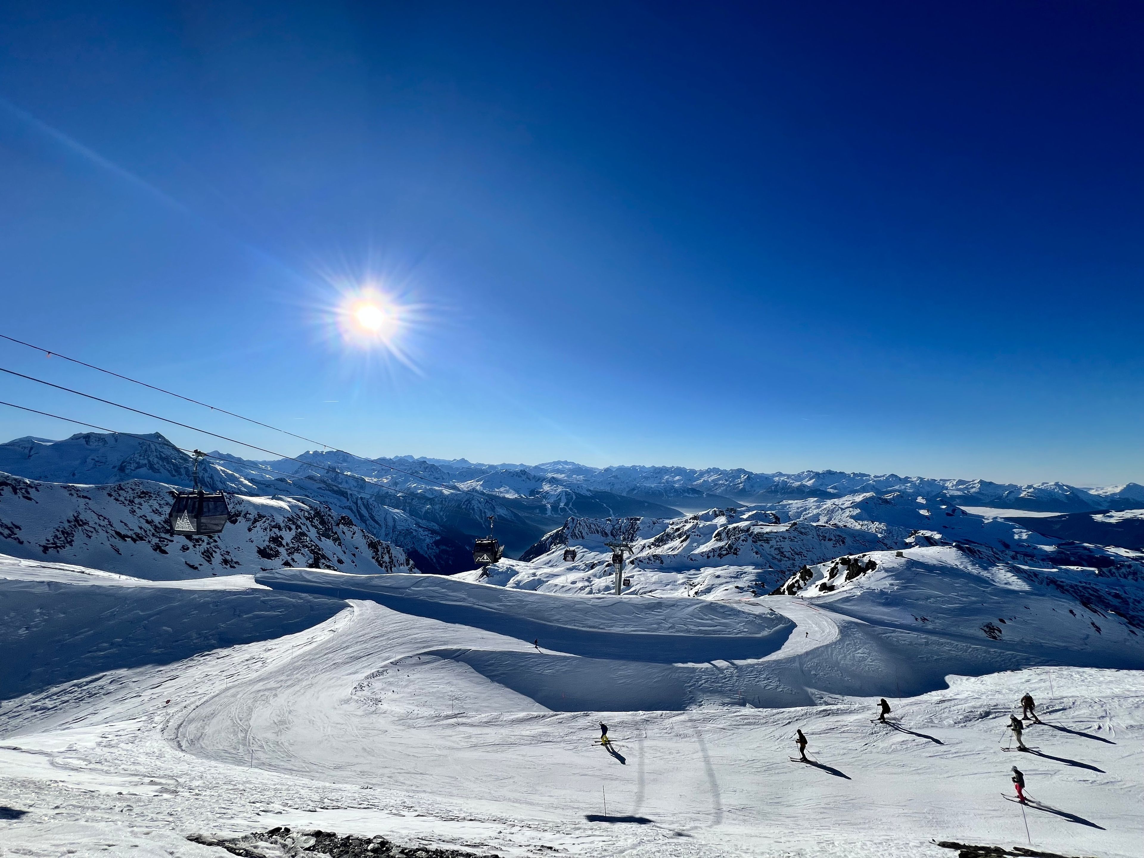 Une piste de ski sous un ciel dégagé, avec un soleil éclatant.