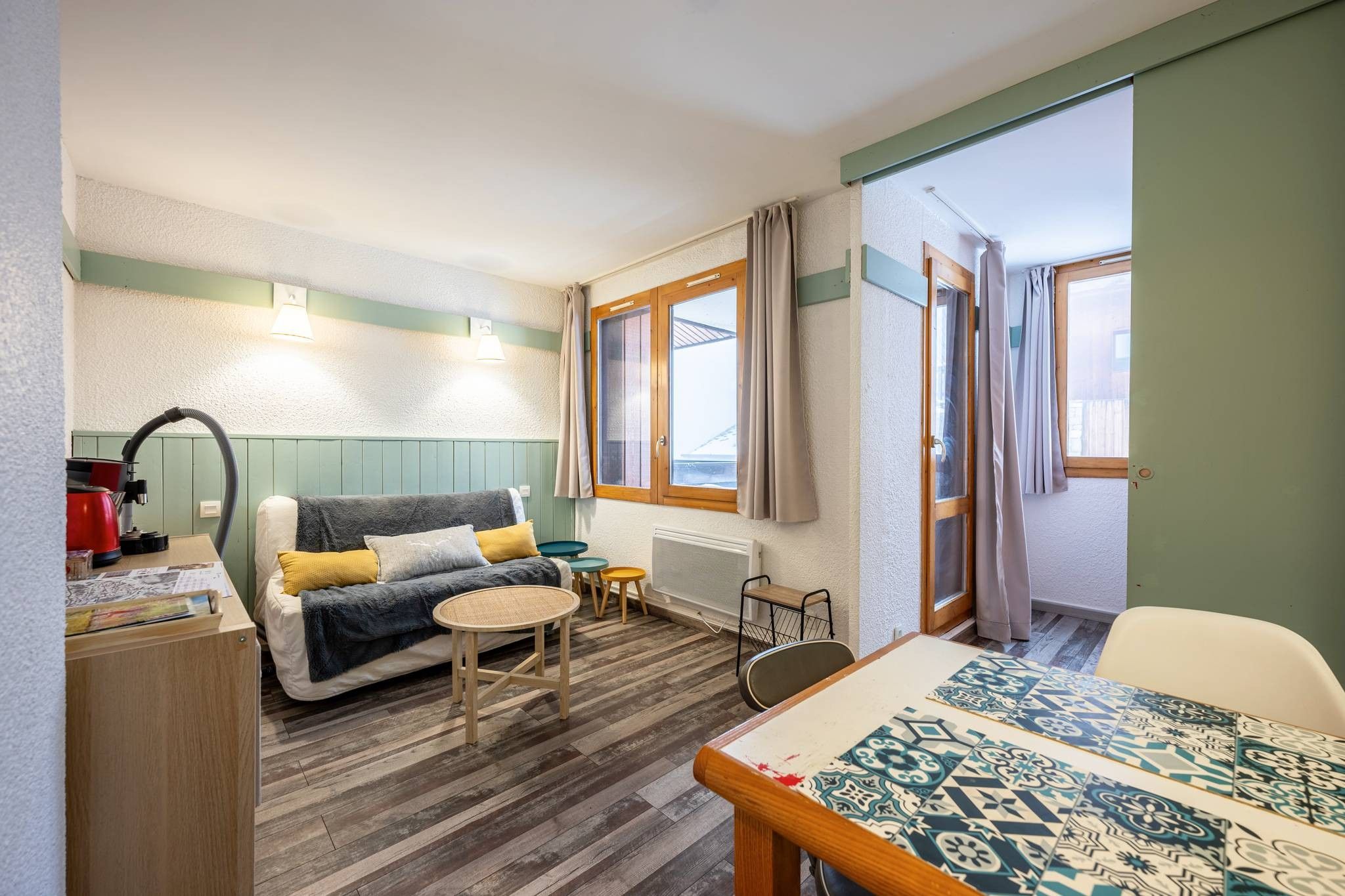 A cozy room with a bed, a small table, a chair, and a radiator.