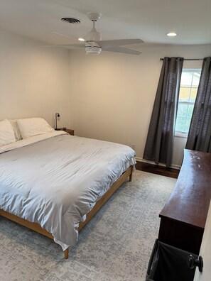 A bedroom with a bed, a ceiling fan, a window with curtains, and a wooden dresser. - Spacious 3-bedroom house for Augusta Masters Week (Martinez)