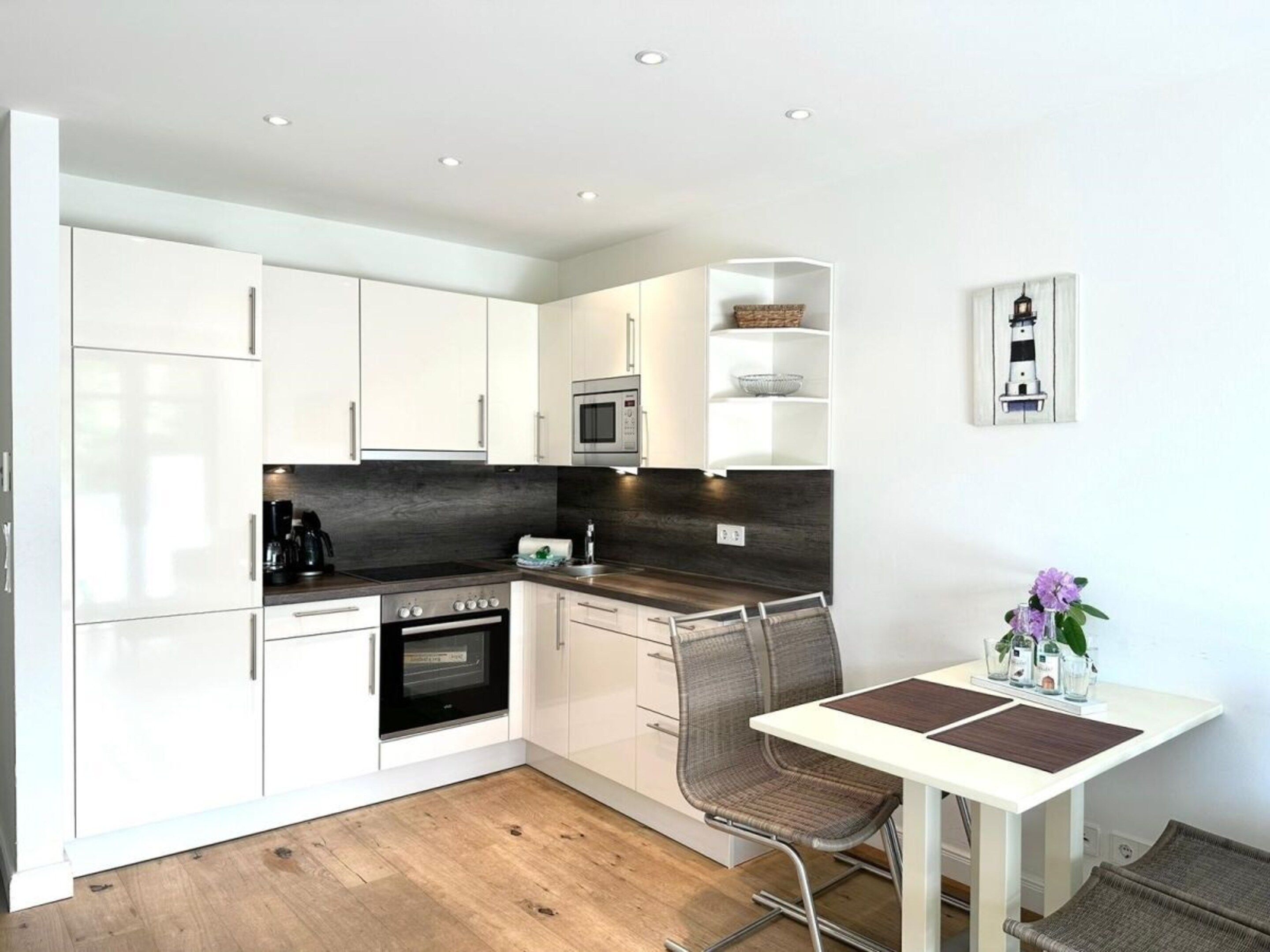 A compact kitchen with white cabinets, a microwave, an oven, and a dining area with a table and chairs.