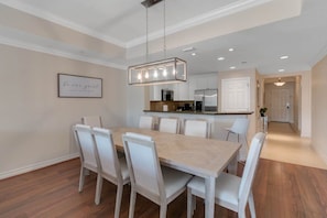 A modern kitchen with white cabinetry, a central island, and a hanging light fixture. - Luxurious Reunion Three Bed, Three Bath - SR001 (Four Corners)