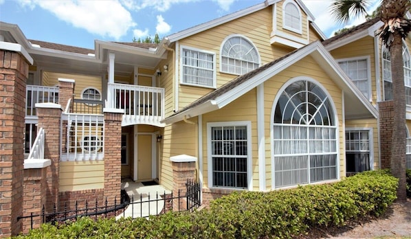A two-story house with a balcony, large windows, and a brick foundation. - Sweet Main Floor Home in Sweetwater - SW001 (Kissimmee)