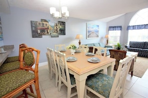 A dining area with a wooden table set for four, surrounded by white chairs with patterned cushions. - Sweet Main Floor Home in Sweetwater - SW001 (Kissimmee)