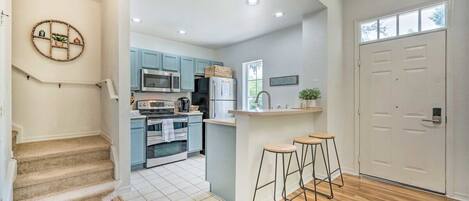 Una cocina moderna con armarios azul claro, una isla central y una escalera de madera.