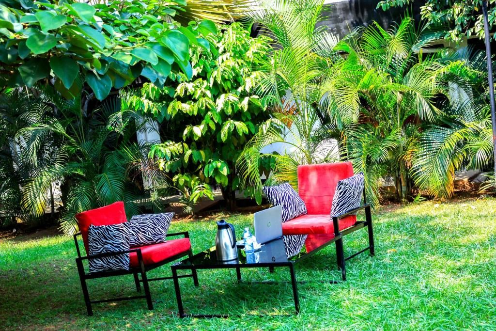 An outdoor seating area with two red chairs and a black table, surrounded by lush greenery.