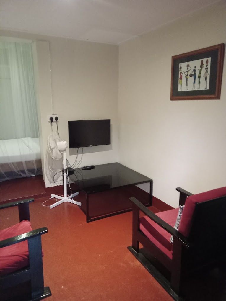 Una habitación de hotel con una cama, un escritorio, una silla, un televisor y un cuadro colgado en la pared.
