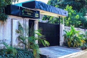 Entrada de un hotel con un cartel que dice 'Gold Palm Hotel' y 'Paraíso Africano por Excelencia'.