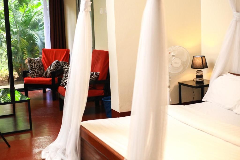 Habitación de hotel con cama, una silla con cojines de estampado de cebra, una mesita de noche con lámpara y vistas a zonas verdes.