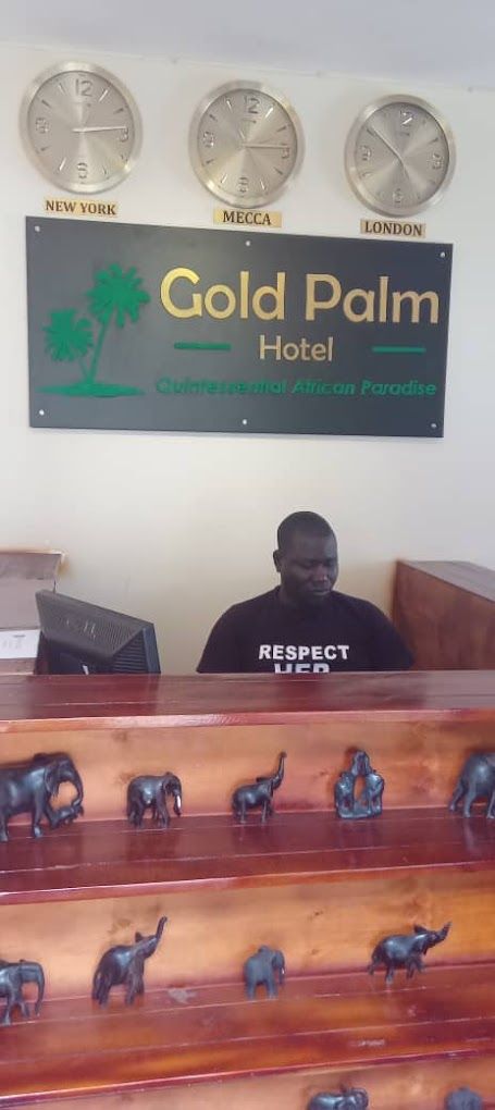 Una recepción con un cartel de Gold Palm Hotel, que muestra relojes para Nueva York, La Meca y Londres.