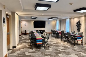 A conference room with a long table, chairs, a flat-screen TV, and a clock on the wall. - ADA Suite w/ Kitchen | Free Breakfast & Shuttle (Houston)