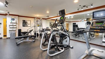 Une salle de sport équipée de divers appareils d’exercice, notamment un tapis de course, un vélo elliptique et des appareils de musculation.