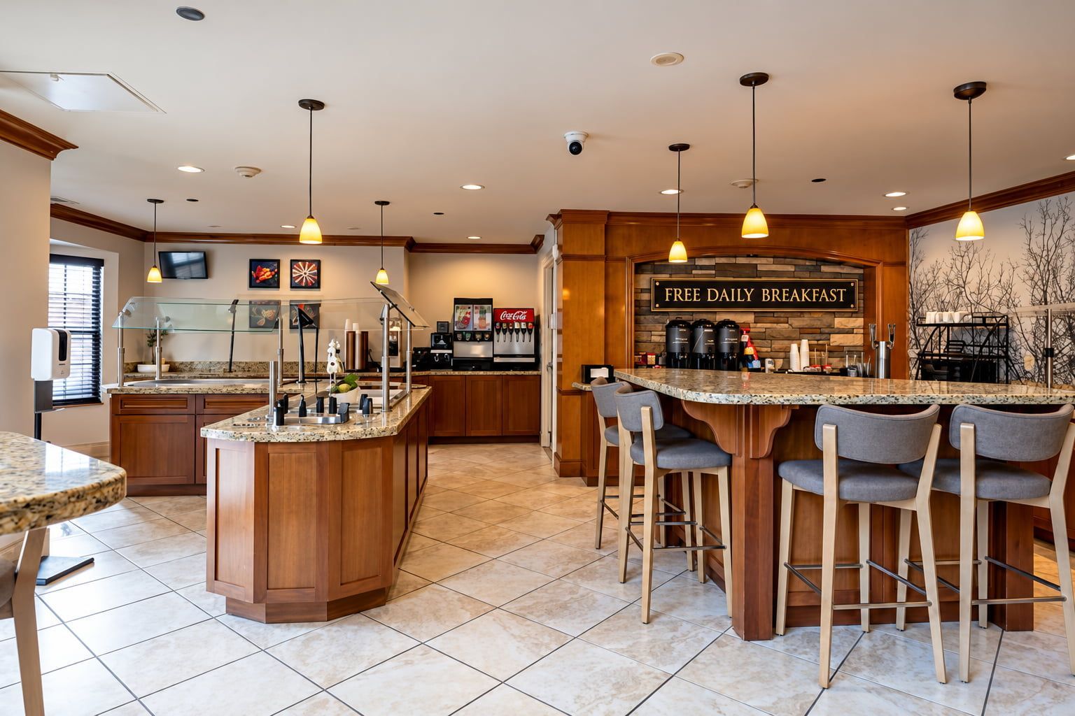 Una cocina moderna con una isla central, taburetes de bar y un cartel que anuncia desayuno diario gratuito.
