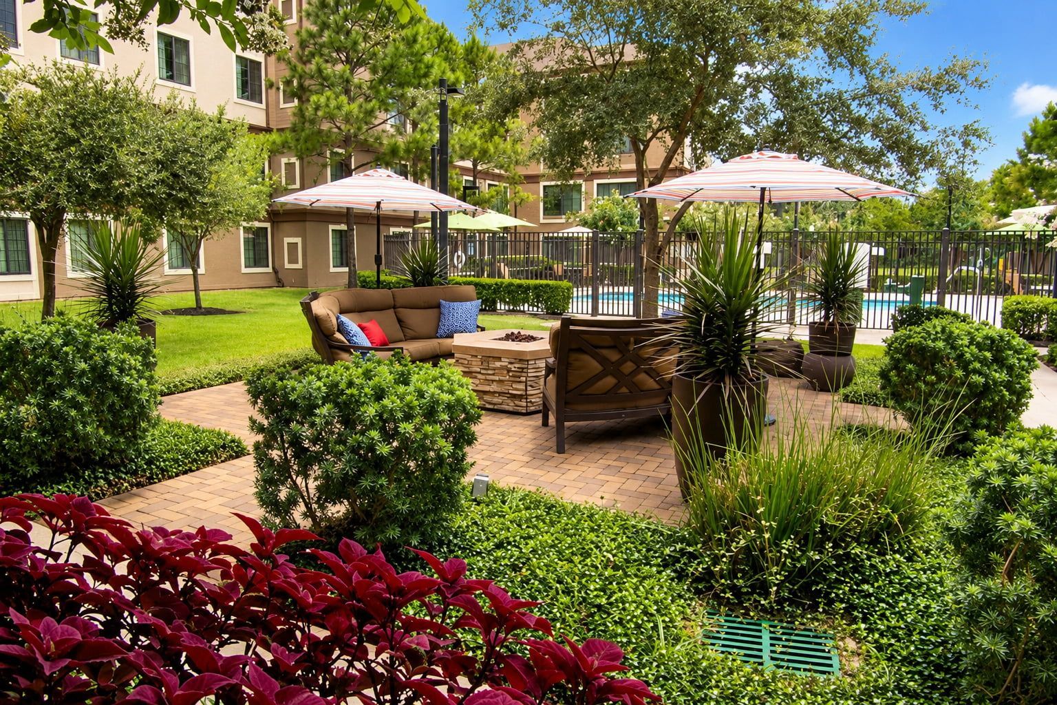 Un patio con mobiliario exterior, piscina y abundante vegetación.