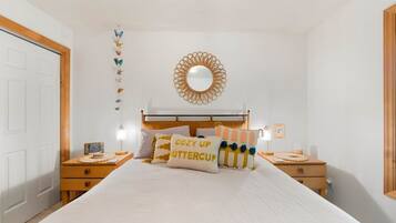 Een slaapkamer met een bed, twee nachtkastjes, een spiegel aan de muur en een decoratieve vlinder aan de wand.