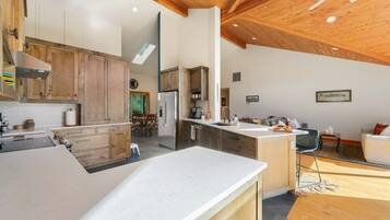 Cozinha moderna com armários de madeira, uma ilha grande e uma área de jantar com mesa e cadeiras.