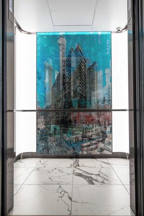 An elevator with a glass wall reflecting a cityscape with tall buildings and a busy street scene. - Deluxe Living in Yorkville Stylish 2-BR Condo (Toronto)