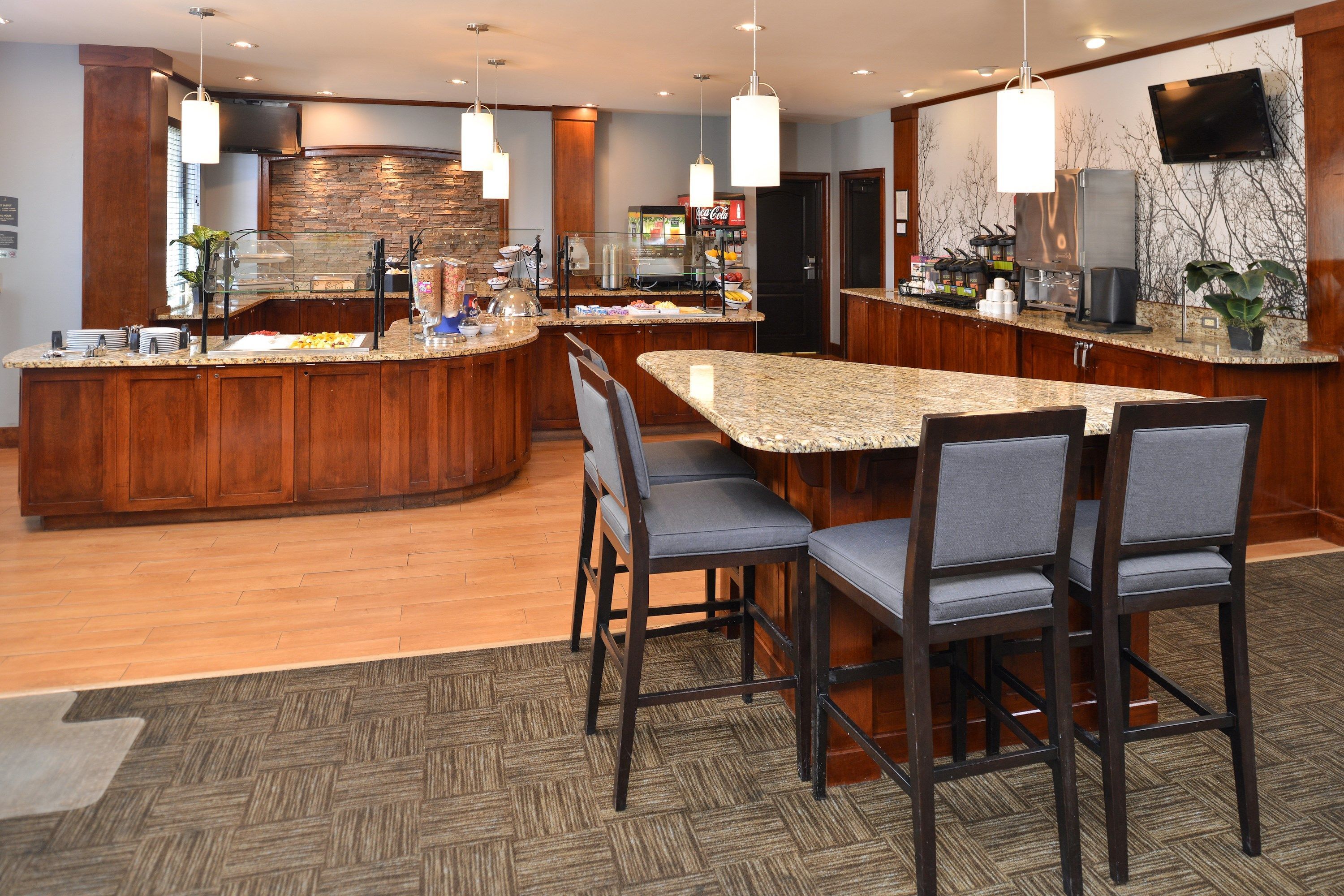 A modern kitchen with a granite countertop, wooden cabinets, and a central island with bar stools.