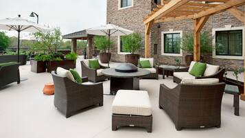 An outdoor patio area with wicker furniture, a round table, and potted plants.