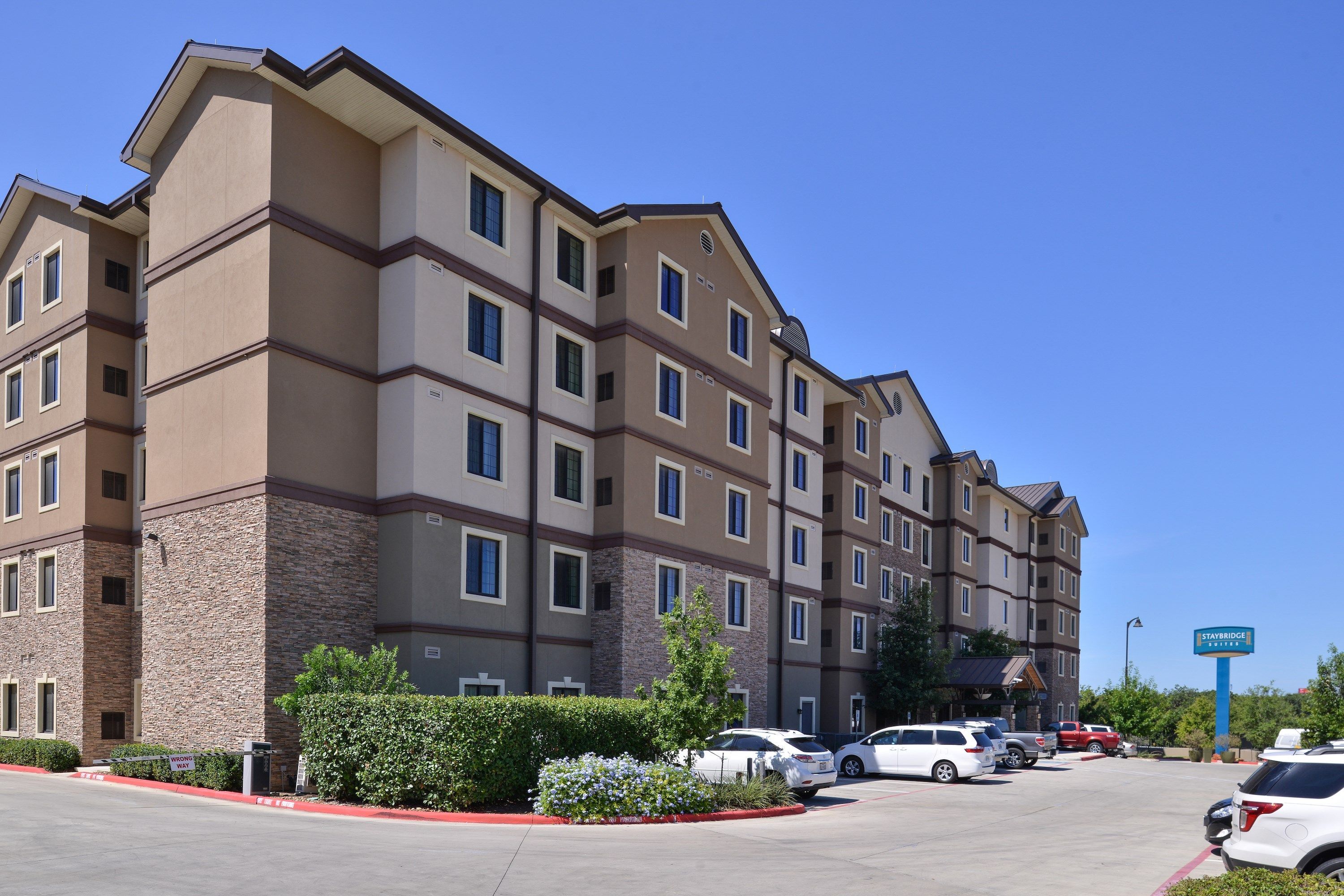 A multi-story hotel with a parking lot in front.