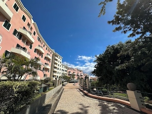 A multi-story hotel with balconies, a paved walkway, and surrounding greenery. - Cozy Duplex Retreat by Green Parc & Ocean View (Funchal)