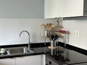 A modern kitchen with a stainless steel sink, black countertops, and white tiled backsplash. - Cozy Duplex Retreat by Green Parc & Ocean View (Funchal)