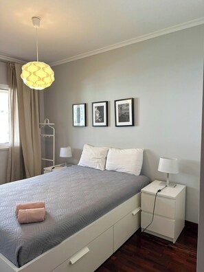 A bedroom with a bed, bedside tables, a hanging light fixture, and three framed pictures on the wall. - Cozy Duplex Retreat by Green Parc & Ocean View (Funchal)