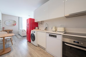 A modern kitchen with a dishwasher, oven, and red refrigerator. - Excellent Carmo Suite – Stylish Apartment Old Town (Funchal)