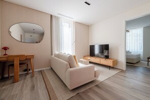 A modern living room with a sofa, TV, and a desk with a chair. - Excellent Carmo Suite – Stylish Apartment Old Town (Funchal)