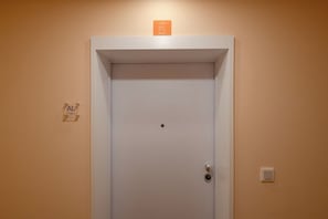 A white door with a small sign above it, a lock, and a light switch on the wall. - Carmo Luxury 2L · Luxury Carmo Suite Elegant Stay (Funchal)