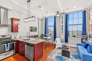 A modern kitchen with a built-in stove, dishwasher, and a dining area with a round table and chairs. - Bright Hip 1BD Sanctuary | Historic Spots | Max 2 (Philadelphia)