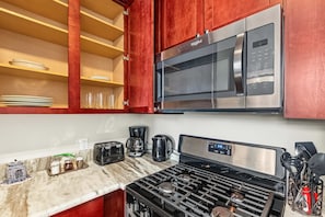 A kitchen with a stainless steel microwave, a gas stove, and a coffee maker. - Vibrant Home 1BD | Quick Transit Sights | Stay 2 (Philadelphia)
