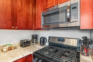 Une cuisine équipée d’un four à micro-ondes en acier inoxydable, d’une cuisinière à gaz, d’un grille-pain et d’une machine à café.