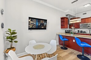 Cozinha moderna com televisão de tela plana, armários de madeira e um espaço de bar com banquetas azuis.