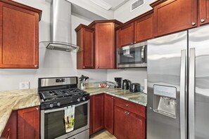 A modern kitchen with stainless steel appliances, wooden cabinets, and a marble countertop. - Sleek City Nest 1BD | Walk to N Liberties | Fits 2 (Philadelphia)