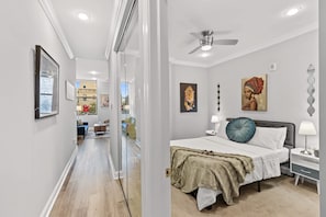 A hotel room with a bed, nightstands, a ceiling fan, artwork, and a view through a glass door. - Sleek City Nest 1BD | Walk to N Liberties | Fits 2 (Philadelphia)