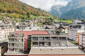 A town with a mix of traditional and modern buildings, a prominent red building in the foreground, and a mountainous backdrop. - New Listing (Engelberg)