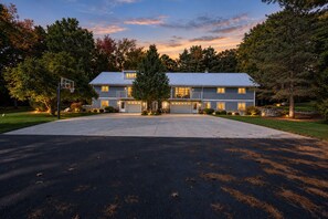 Une maison d’habitation à deux étages, avec une allée, un jardin devant et des arbres.