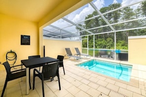 An indoor swimming pool area with a glass enclosure, a table with chairs, and a sign on the wall. - Serenity 3BR Townhome w/ Private Pool (Clermont)