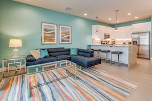 A living room with a sectional sofa, a glass coffee table, and a colorful striped rug. - Serenity 3BR Townhome w/ Private Pool (Clermont)