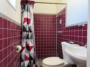 A bathroom with a toilet, sink, and shower area. - A-Town Motel (Arnett)