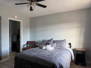 A bedroom with a bed, a nightstand, a chair, a desk, and a ceiling fan. - A-Town Motel (Arnett)