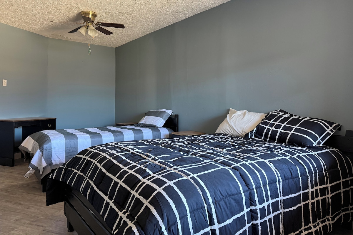 A bedroom with two beds, a ceiling fan, and a desk.